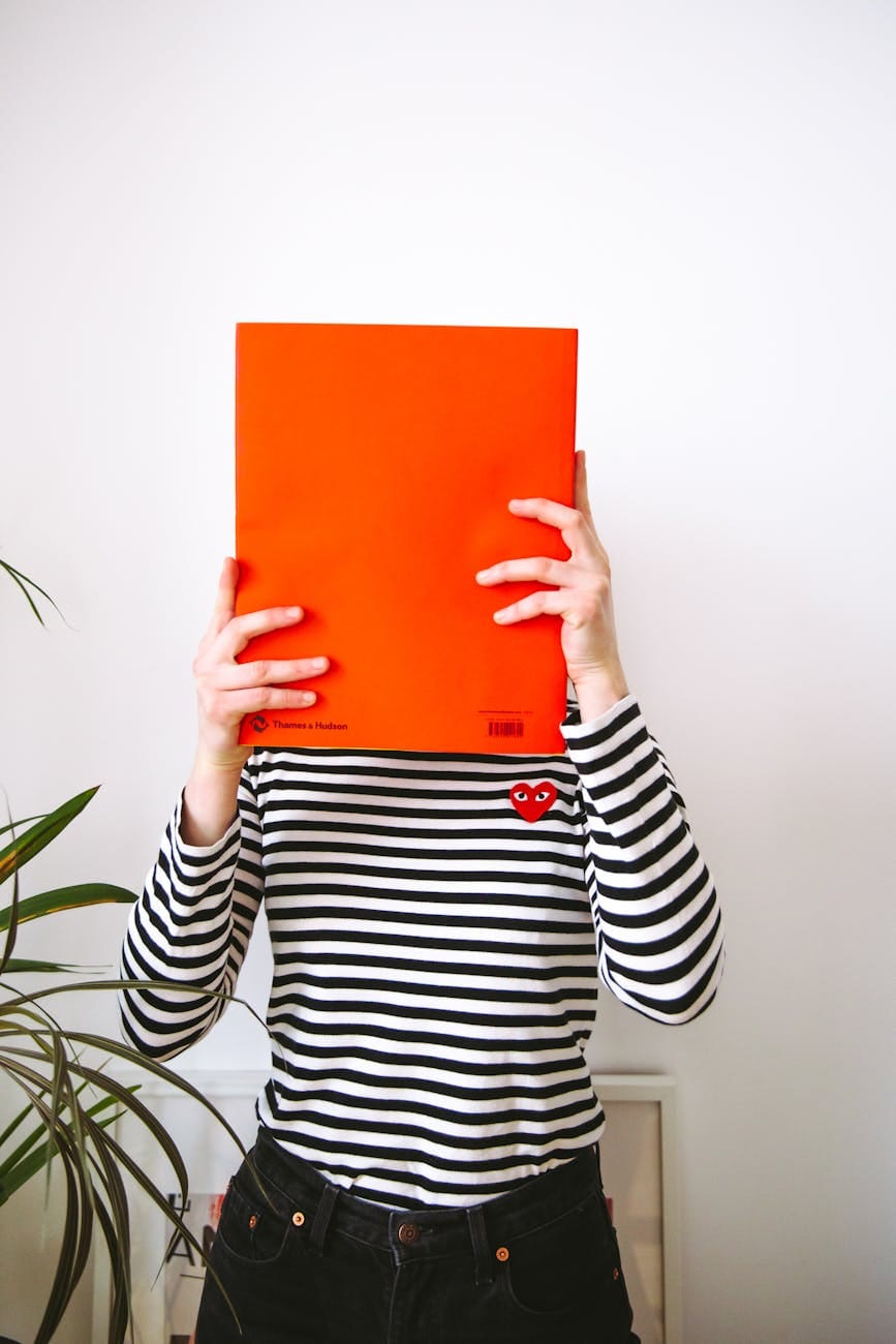 woman in black and white striped long sleeve shirt holding orange paper