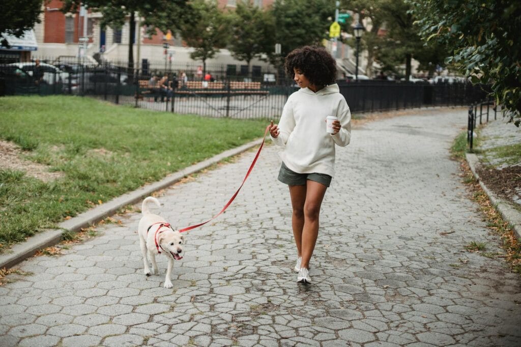 black woman with coffee walking dog